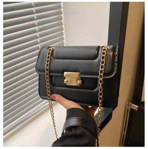 Detail of black padded chain bag with horizontal stitching and gold metal buckle