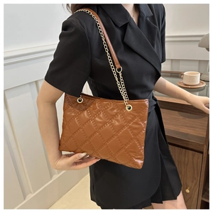 Detail of vintage brown quilted tote bag with gold chain strap shown on shoulder
