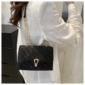 Close-up of black quilted velvet crossbody bag with gold U-shaped buckle and chain strap