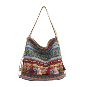 Ethnic tote bag with geometric wave patterns and colorful tassels on a white background