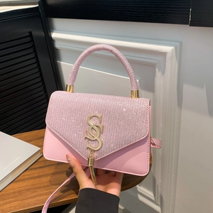 Pink sequin crossbody bag with gold SS logo and chain tassel detail on wooden table