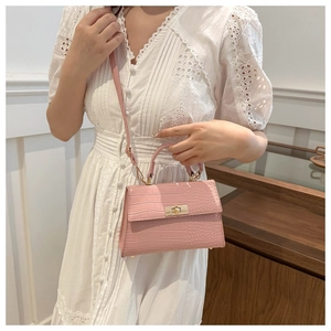 Detailed view of pink croc-embossed leather handbag with gold metal twist lock buckle