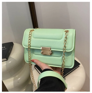 Close-up of mint green chain bag featuring horizontal stitching and gold metal lock