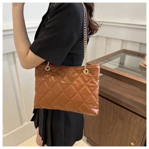 Close-up of brown quilted faux leather texture with gold chain strap on shoulder bag