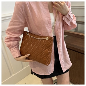 Detailed view of the dark brown quilted chain strap bag worn with an elegant outfit