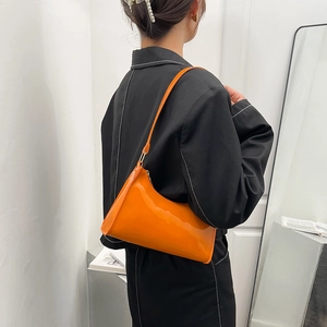 Minimalist orange patent leather baguette bag with a sleek shoulder strap for women