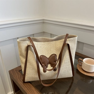Chic woven straw tote bag with brown leather bow and handles for summer vacation style