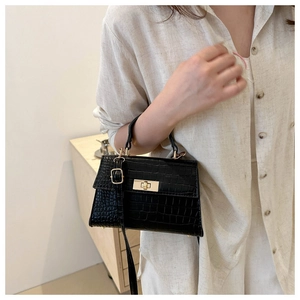 Detail showing black croc-embossed leather texture and gold metal flip lock on handbag