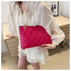 Close-up of vibrant fuchsia quilted bag with golden chain strap on a model shoulder