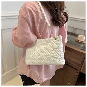 Vue latérale du sac bandoulière blanc matelassé avec chaîne dorée porté par un modèle