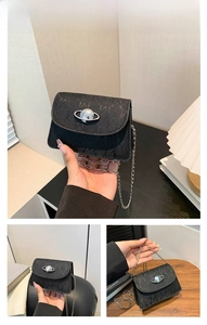 Detail of black leather mini bag featuring M-pattern texture and silver saturn logo