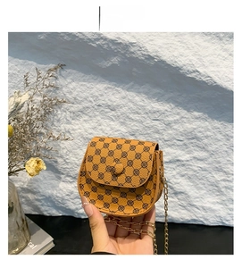 Detailed macro view of mini brown saddle bag with vintage clover print and gold chain strap
