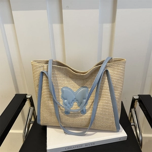 Summer straw tote bag with blue trim and butterfly patch on a wooden background