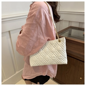 Détail de la texture matelassée blanche et de la chaîne dorée du sac cabas tendance