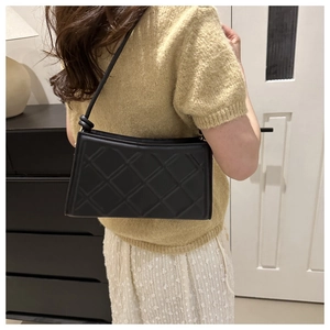 Detail showing the quilted pattern and knot design of the black shoulder bag for women