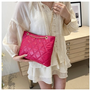 Close-up of pink quilted faux leather shoulder bag with elegant gold chain strap detail