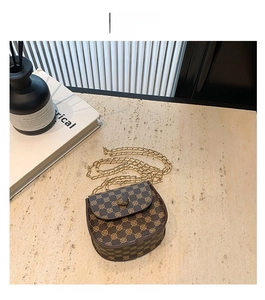Detailed shot of coffee vintage patterned saddle bag with gold chain on stone surface
