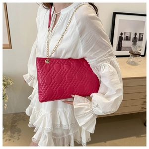 Détail du sac matelassé rose vif avec bandoulière chaîne dorée sur robe en dentelle