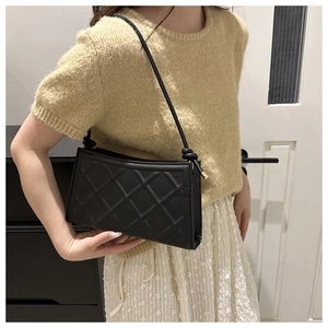 Détail du sac à bandoulière noir en similicuir matelassé avec une sangle minimaliste