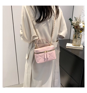 Detailed view of pink quilted leather box bag with chain strap and top handle style