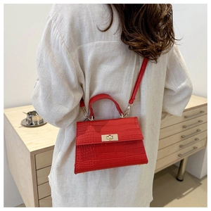 Detail of red crocodile texture handbag featuring gold hardware on a linen outfit