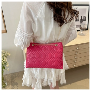 Detail of pink quilted handbag with gold chain strap on model in vintage interior
