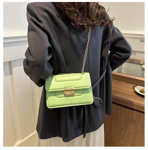Detail of light green quilted crossbody bag with gold chain strap and metal clasp closure