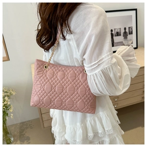 Pink quilted chain shoulder bag shown on model with soft padding and golden metal chain