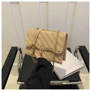 Detail of beige quilted crossbody bag featuring gold-tone chain and textured stitching