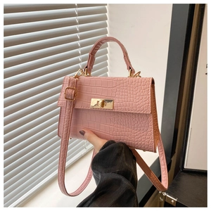 Close-up of pink crocodile texture handbag with gold-tone hardware and rotary lock closure