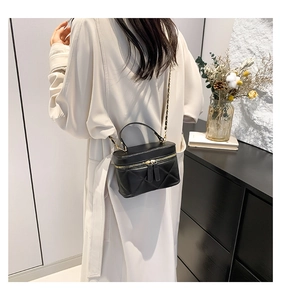 Close-up of a black quilted leather crossbody bag with gold chain and dual zipper detail