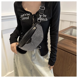 Detail of black leather sling bag with silver rhinestone embellishments and wide strap