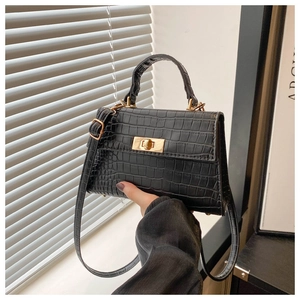Detail of black crocodile texture leather bag with elegant golden metal twist lock closure