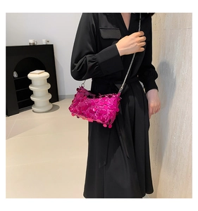 Detail of hot pink sequin crossbody bag with silver chain strap on black dress