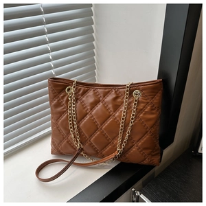 Close-up of brown quilted tote bag showing detailed rhombic stitching and gold chain