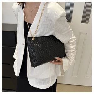 Detail of black quilted faux leather bag featuring elegant gold chain strap and stitching