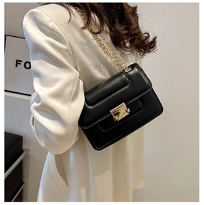 Detail view of the black leather bag golden metal lock and elegant chain strap
