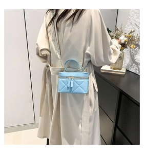 Detail of light blue quilted crossbody bag with gold chain strap and top handle