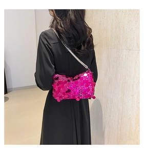Detail of hot pink sequin evening bag with silver chain strap on a black dress