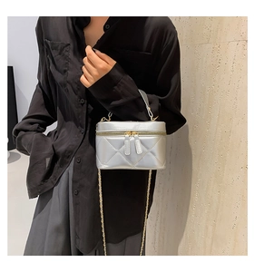 Detail view of silver quilted leather box bag with gold chain strap on model
