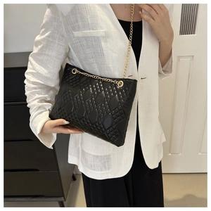 Sac bandoulière matelassé noir classique avec chaîne dorée porté par un mannequin
