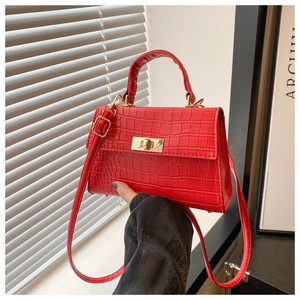 Detail of red crocodile texture handbag with golden twist lock and top handle strap