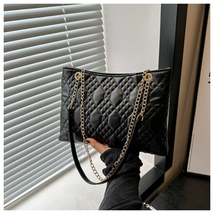 Detail of black quilted leather chain bag with elegant gold metal hardware and texture