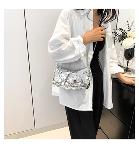 Silver sequin handbag with metal chain strap worn on shoulder for party style
