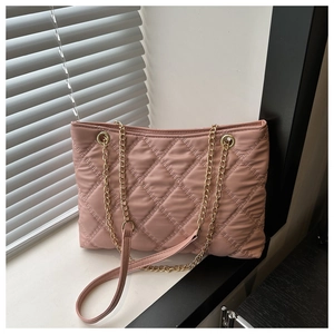 Close-up of pink quilted leather tote featuring golden chain straps and soft lighting