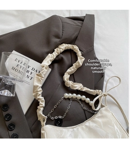 Détail du sac croissant crème avec chaîne en perles, nœud et bandoulière froncée