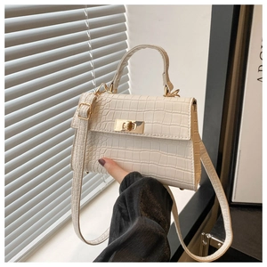 Close-up of cream crocodile pattern handbag with golden twist lock and top handle
