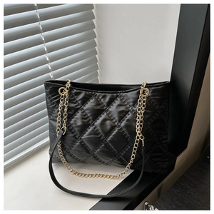 Detail of black quilted tote bag showing premium glossy finish and gold chain straps