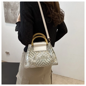 Detail view of vintage embroidered bucket bag with cyan cloud patterns and amber handles