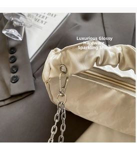 Gros plan du sac en cuir crème avec poignée plissée nuage et détails de chaîne en argent